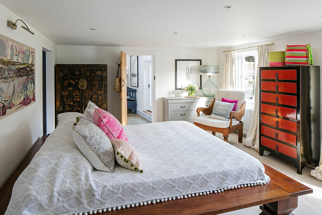 Lacquered chests and platform bed in colonial style bedroom in Victorian cottage Midhurst West Sussex UK