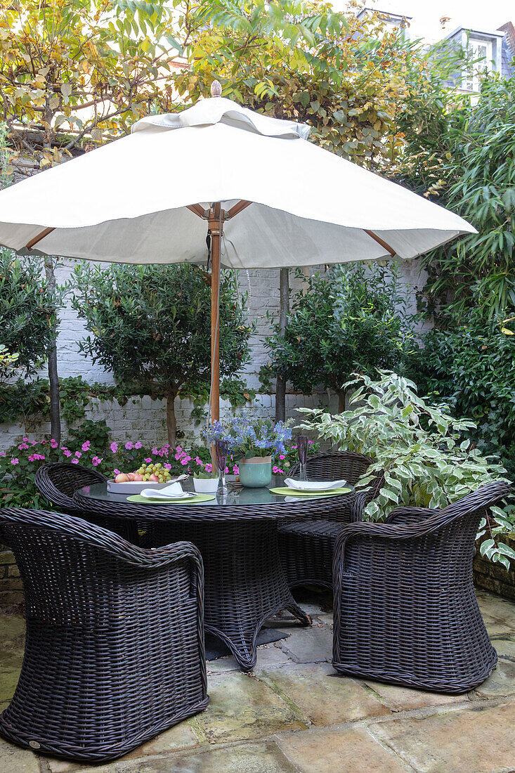 Sonnenschirm und schwarze Korbstühle auf der Terrasse eines viktorianischen Stadthauses London UK