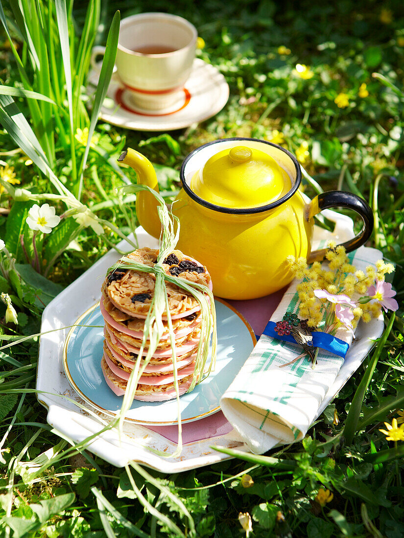 Gelbe Teekanne mit florentinischem Gebäck auf einem Tablett im Garten der Isle of Wight, UK