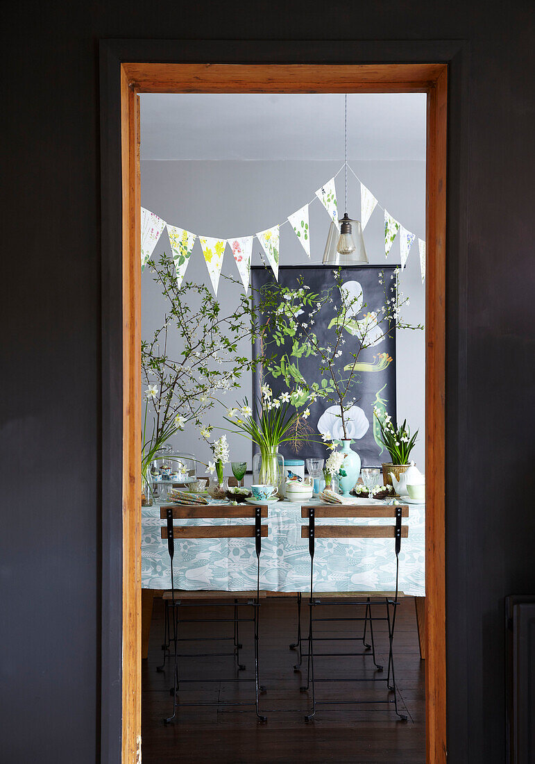 Gedeckter Ostertisch mit Frühlingsblumen durch die Türöffnung