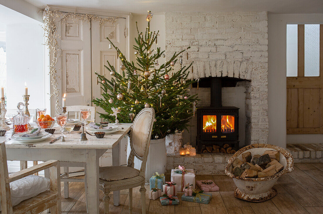 Festive table setting in dining room with decorated Christmas tree and lit candles