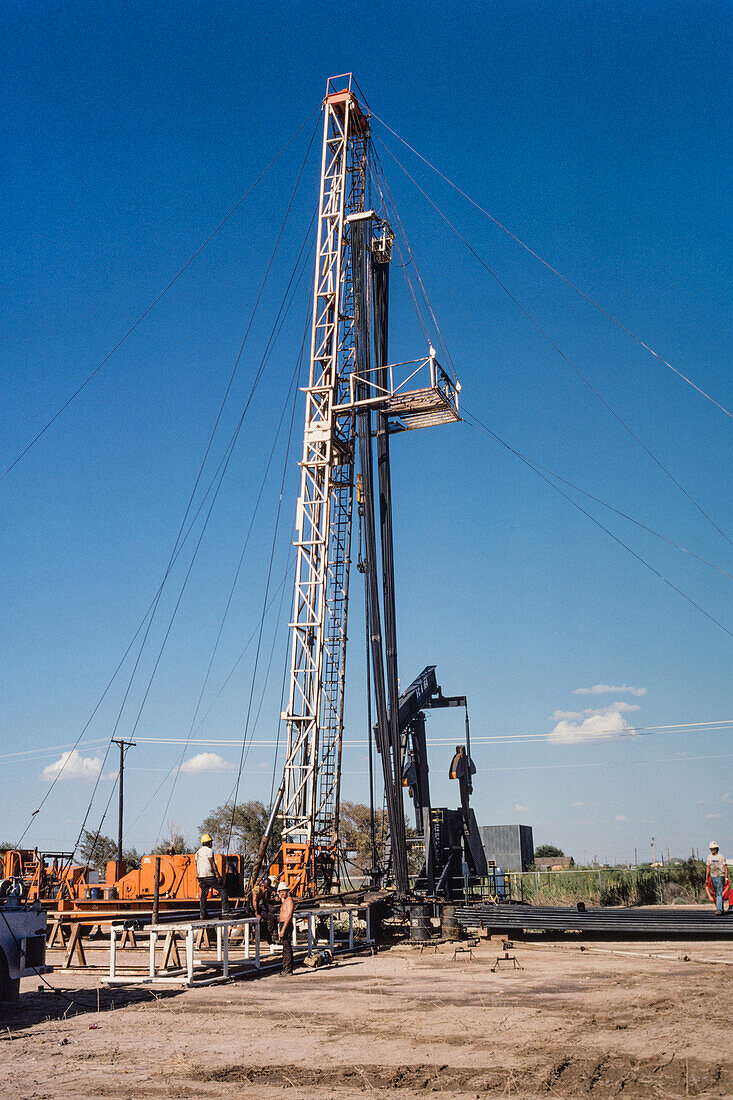Pulling unit crew pulling sucker rods out of oil well