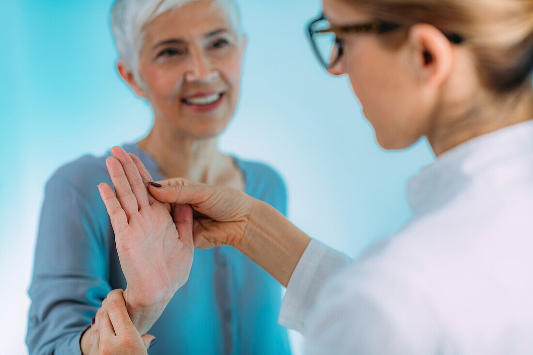 Doctor doing carpal tunnel syndrome test with a senior woman
