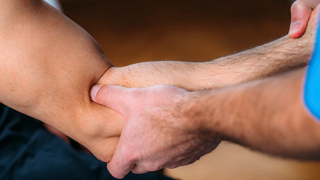 Physical therapist massaging man's arm