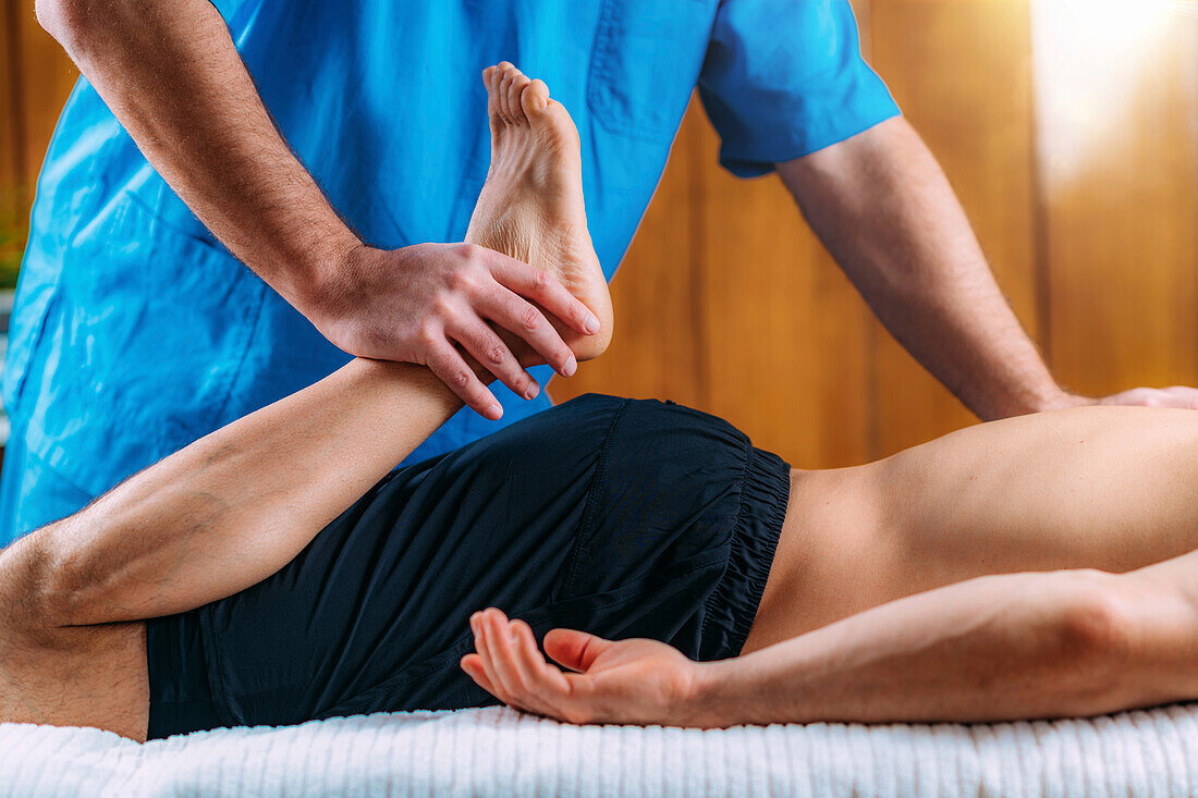 Physical therapist massaging injured leg of a male athlete