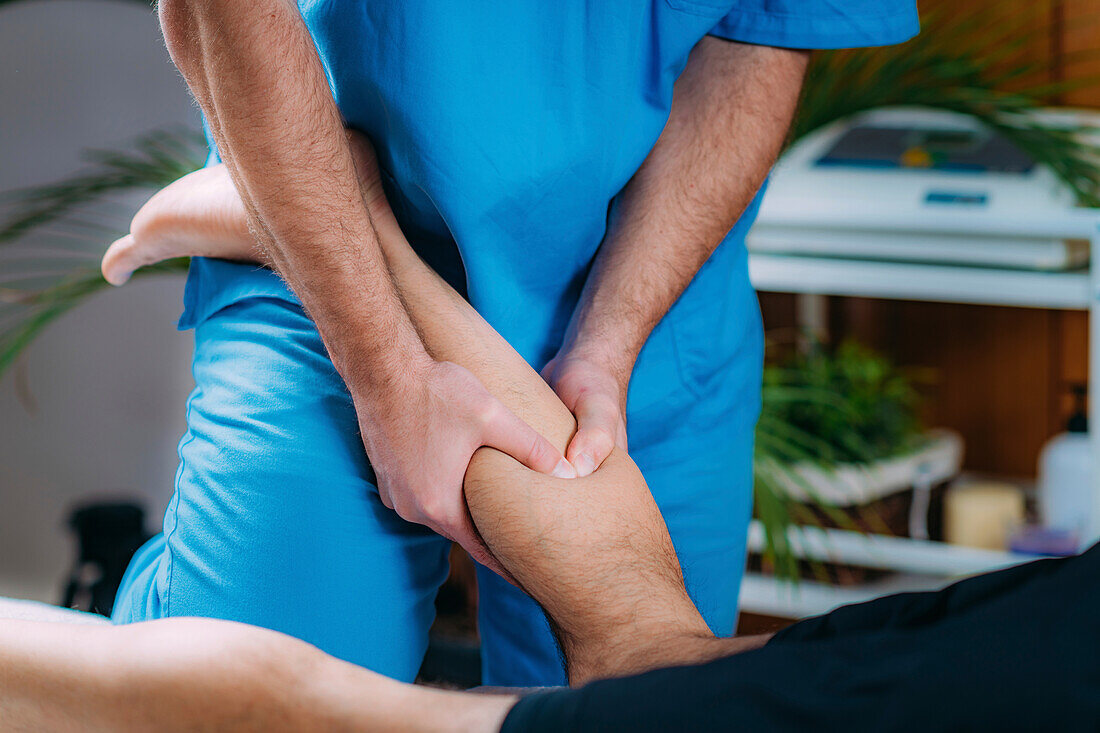 Physiotherapist massaging man with injured calf muscle