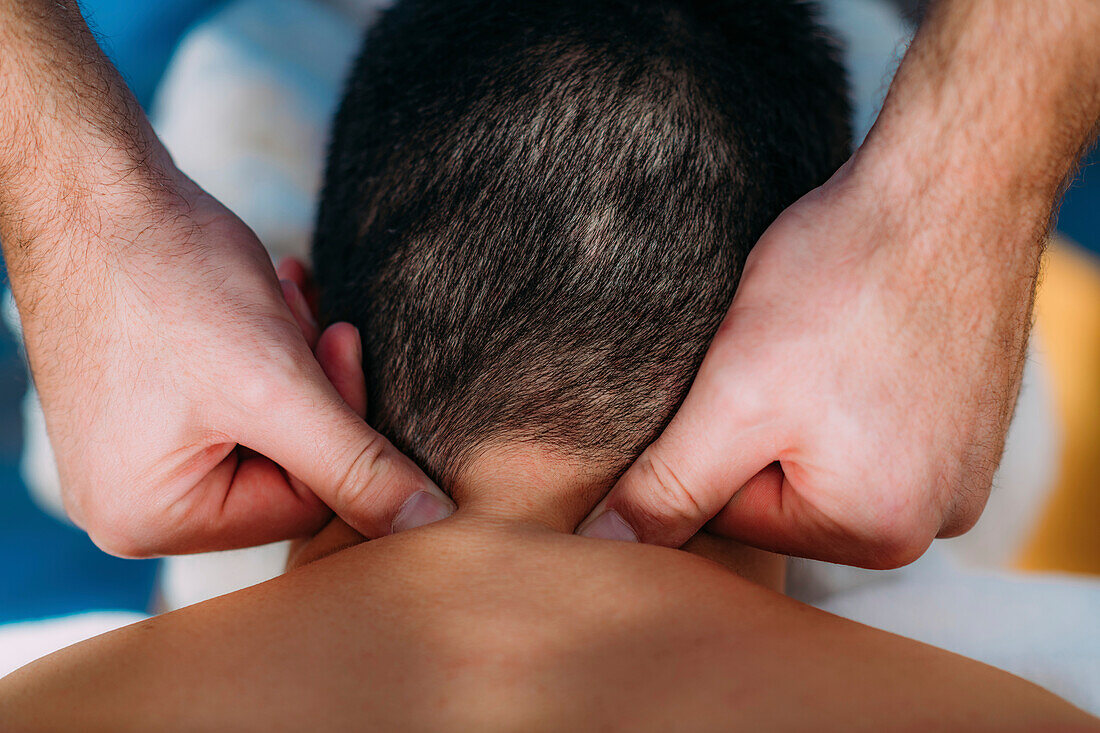 Physiotherapist massaging male patient with injured neck