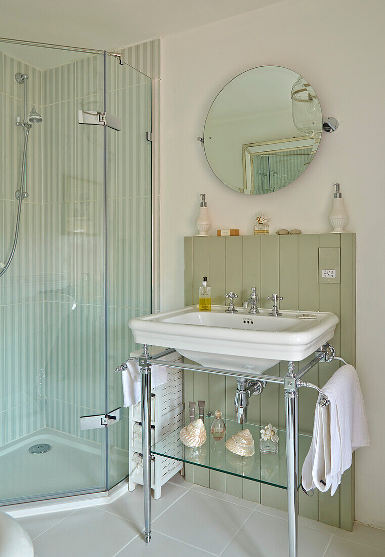 sink with metal frame and round pivot mirror next to a stand up shower