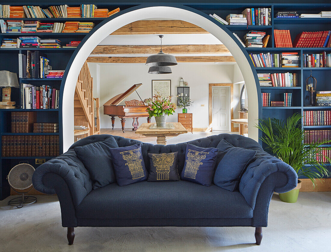 Blue sofa in front of bookshelf, view of dining area with bouquet of flowers