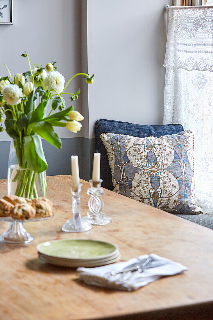 Holztisch mit Blumenstrauß und Kristallkerzenhaltern im Esszimmer