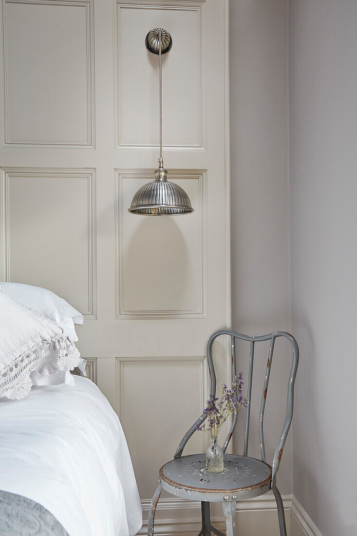 Metal chair and pendant light in bedroom with wall paneling