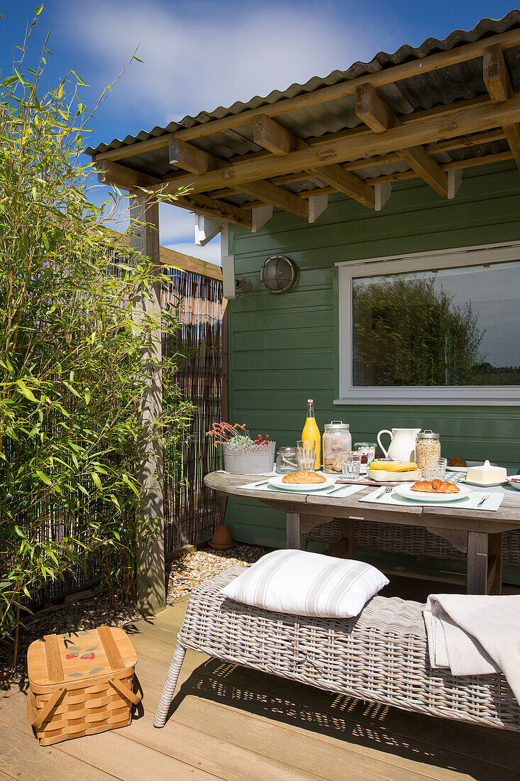 Green painted wooden cottage with patio area