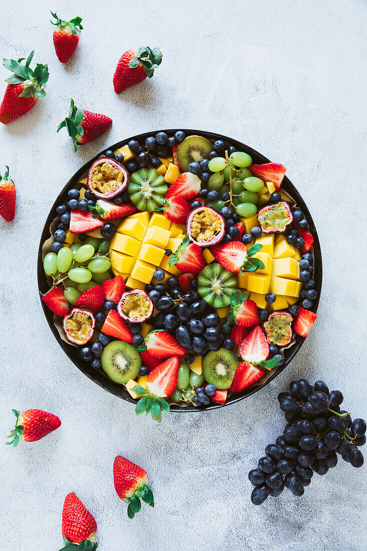 Obstschale mit Mango, Trauben, Kiwi, Erdbeeren und Passionsfrüchten
