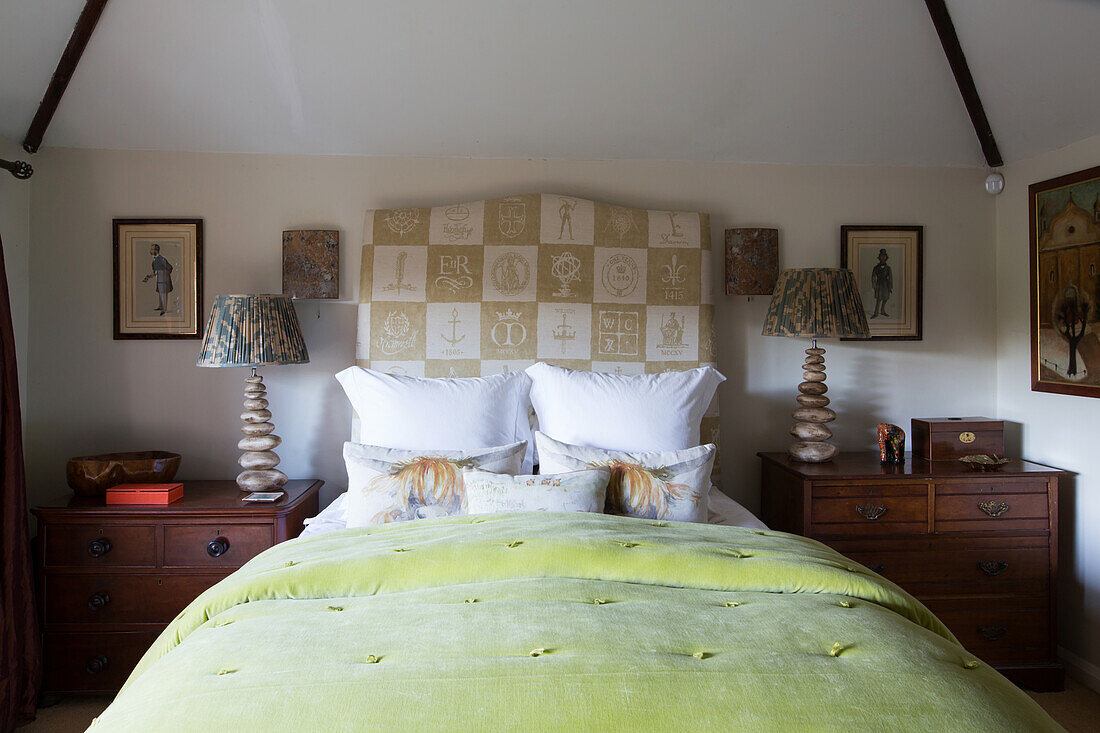 Double bed with high headboard flanked by antique bedside cabinets in rustic bedroom