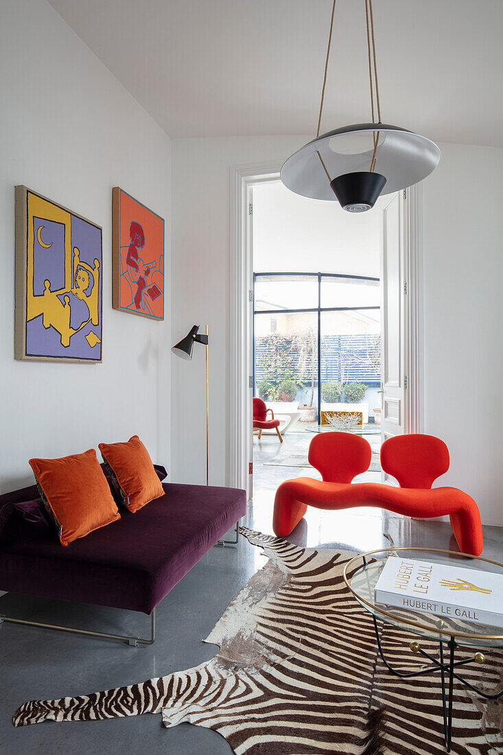 Designer seating in a white living room, round coffee table on a zebra skin rug