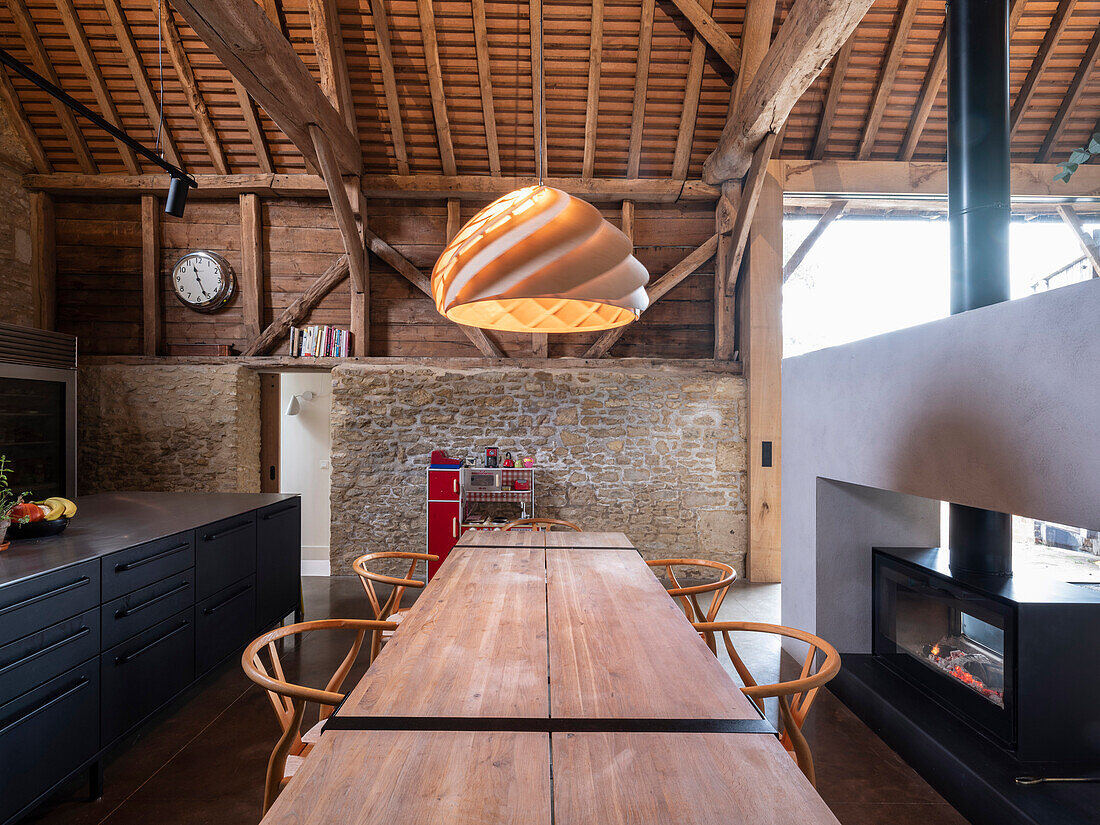 View of open plan kitchen area with large dining table in a former barn