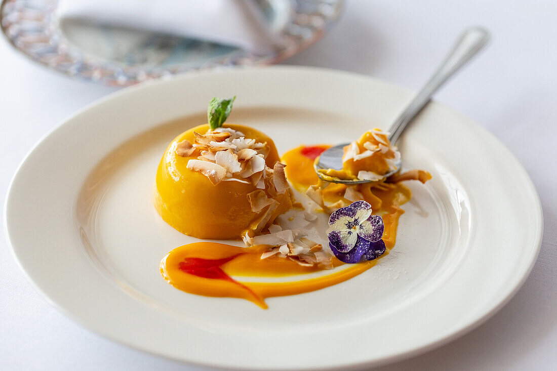 Mango panna cotta with coconut flakes and edible flowers