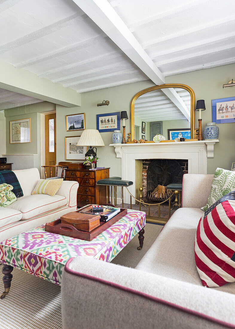 Living room with patterned stool, fireplace and mirror, wooden ceiling and decorative cushions