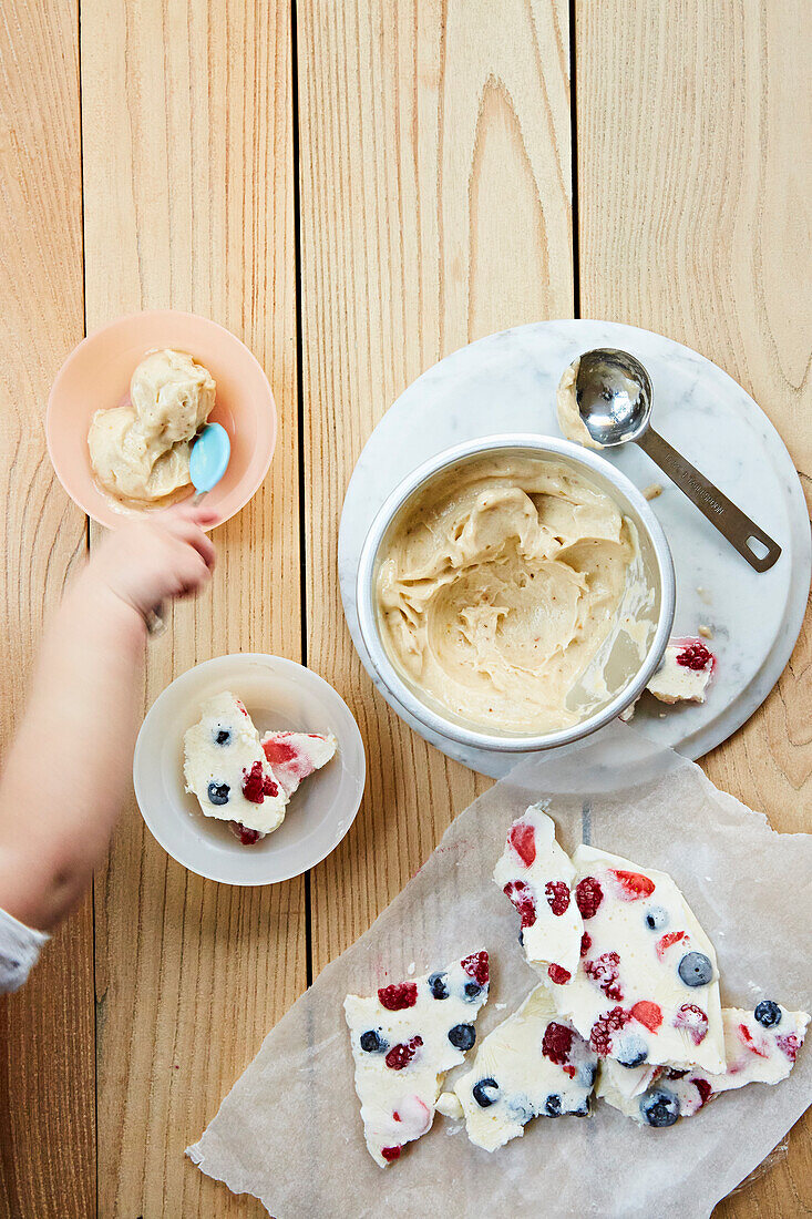 Children s fruit shards and ice cream. A toddler s hand reaching in with a spoon