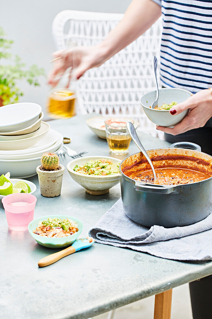 A family meal on an outside table, chilli con carne and smashed avocado