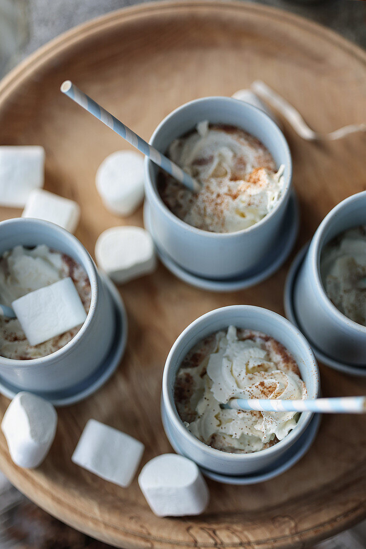 Hot chocolate with whipped cream and marshmallows on a wooden tray