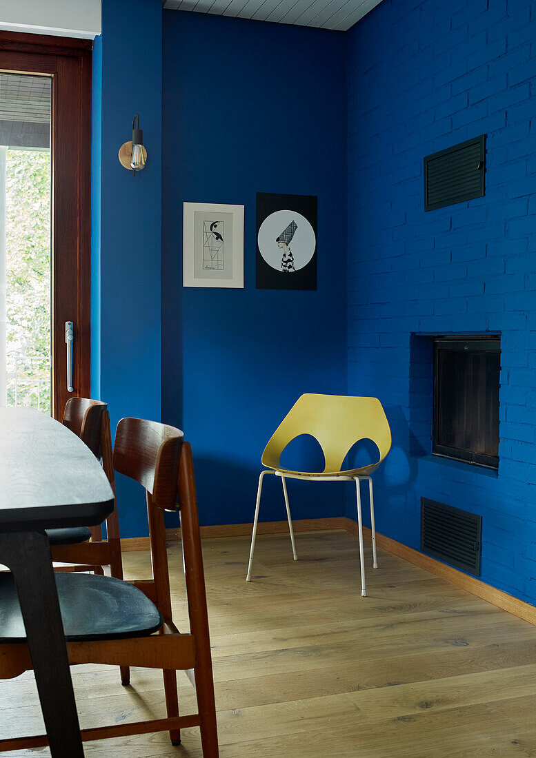 Dining area, blue walls, yellow chair and fireplace