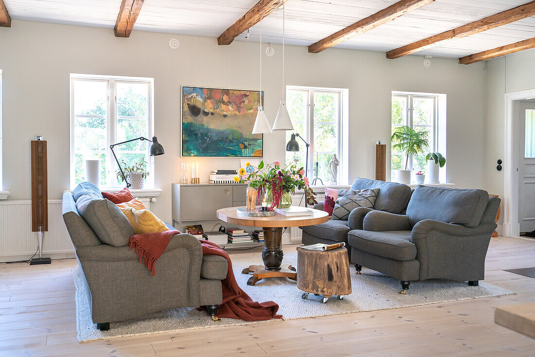 Bright living room with sofa and armchairs in grey and wooden elements