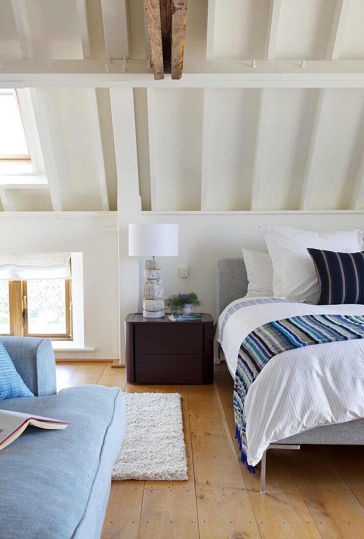 Bright bedroom with exposed beams and striped bed linen