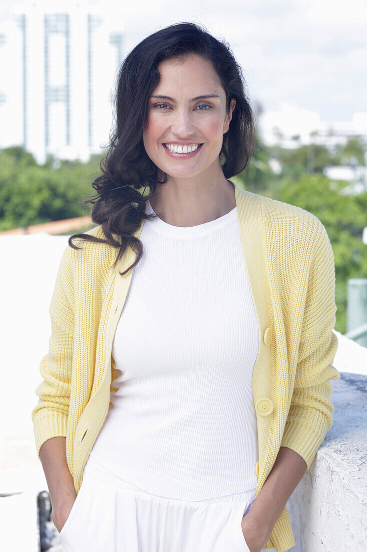 Dark-haired woman in white top and yellow cardigan