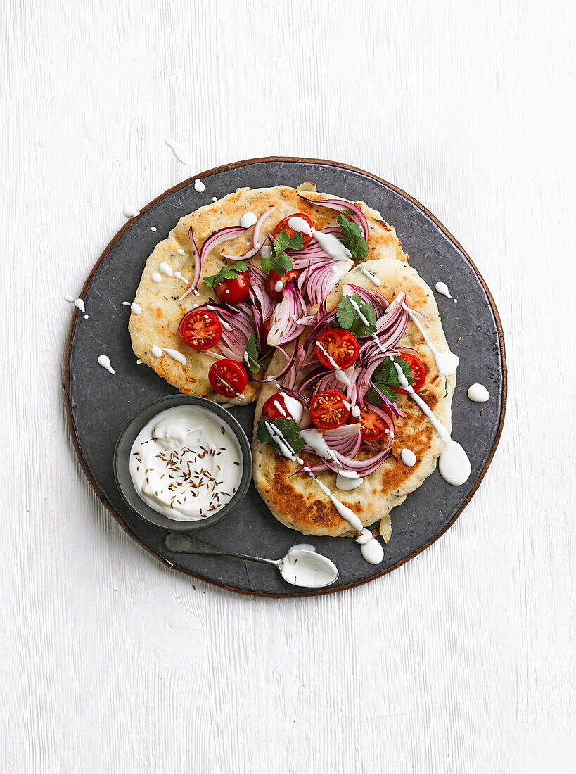 Käse-Naan mit roten Zwiebeln, Kirschtomaten, Kreuzkümmel und Koriander