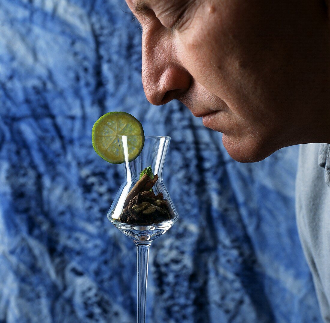 Man smelling schnapps flavours in glass (filled with spices)