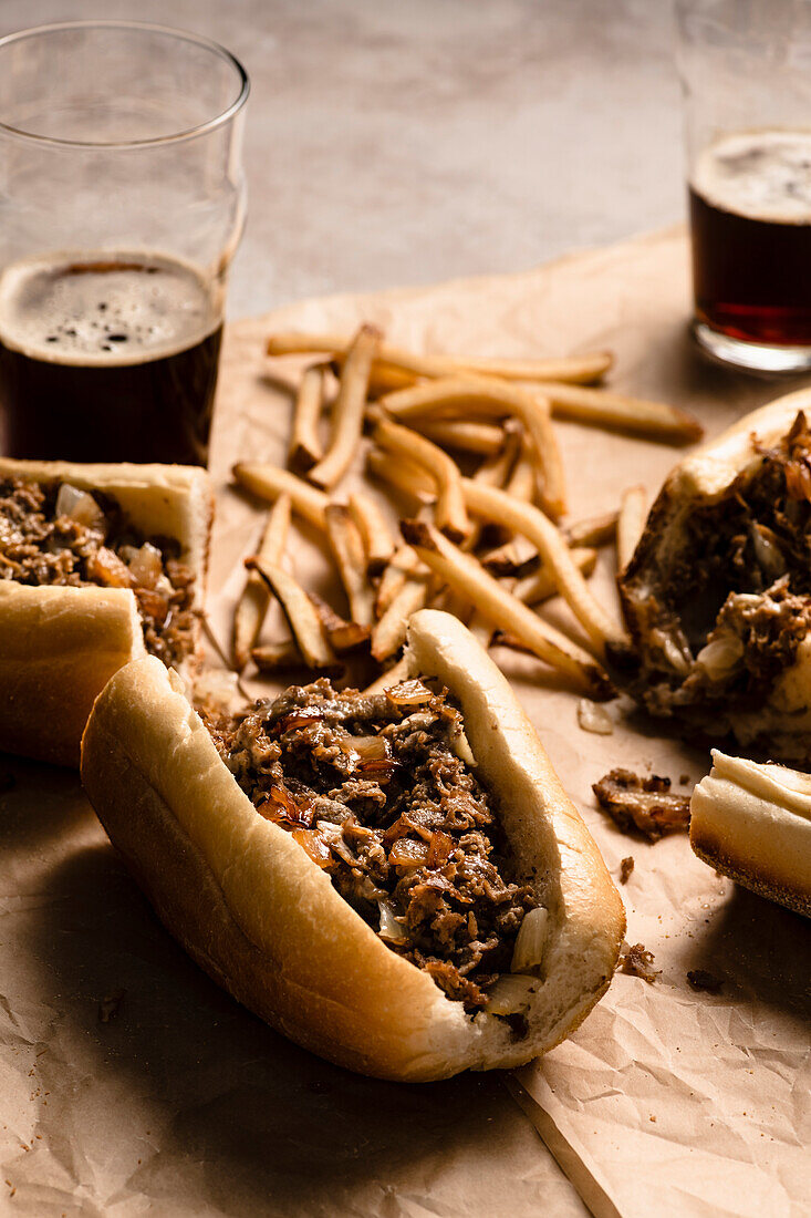 Philly-Cheesesteak-Sandwich (USA) mit Pommes und  dunklem Bier