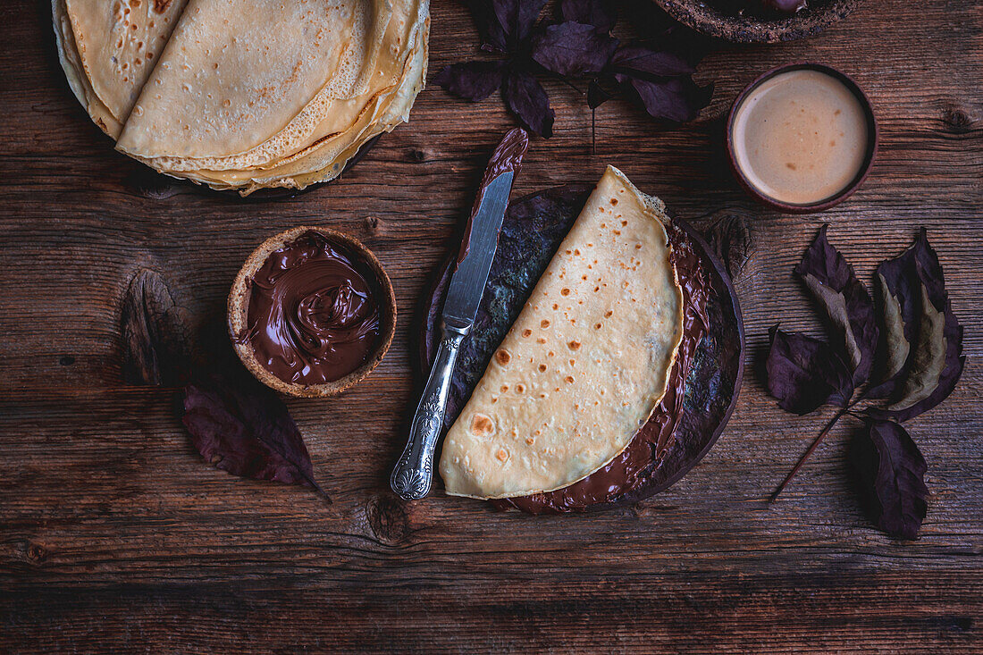 Crepes mit Schokoladenaufstrich auf rustikalem Holztisch