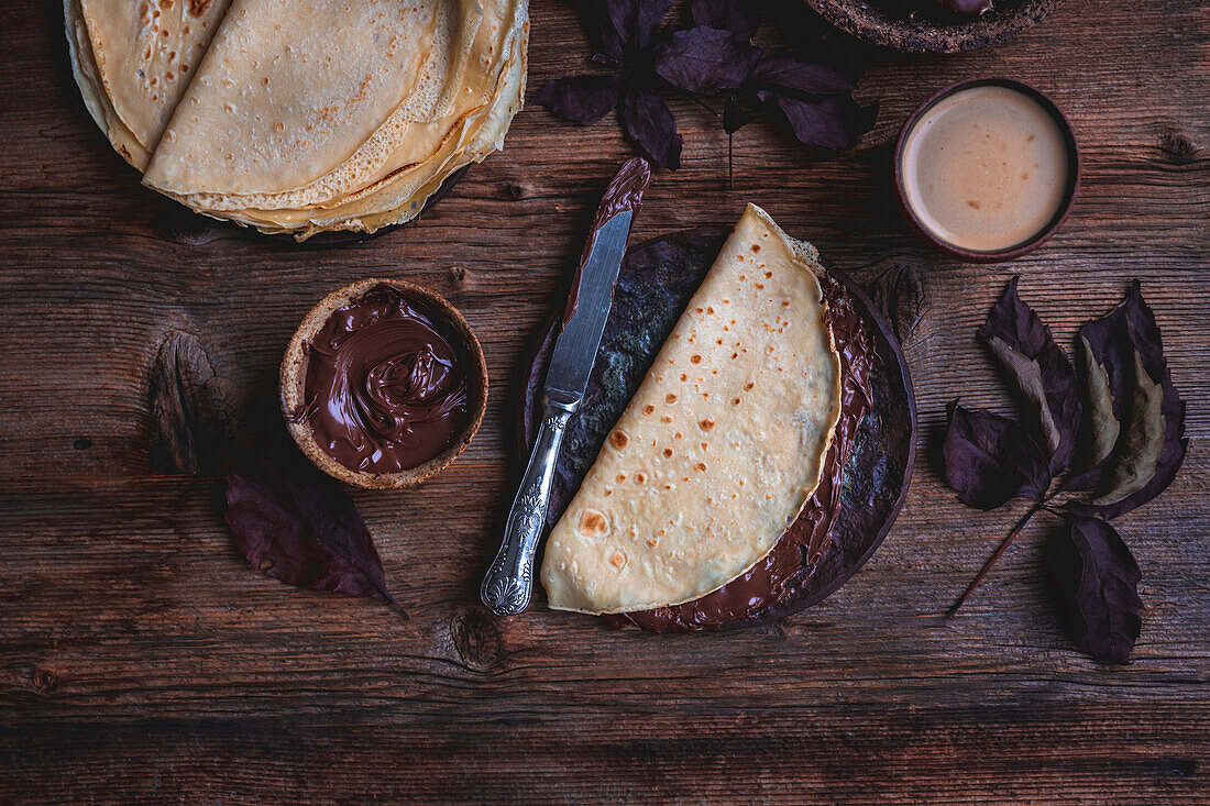 Crepes with chocolate spread on a rustic wooden background