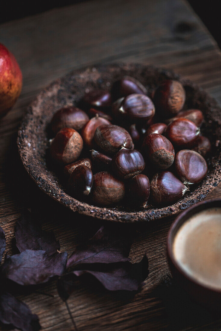 Chestnuts in a small ceramic bowl on a rustic wooden background