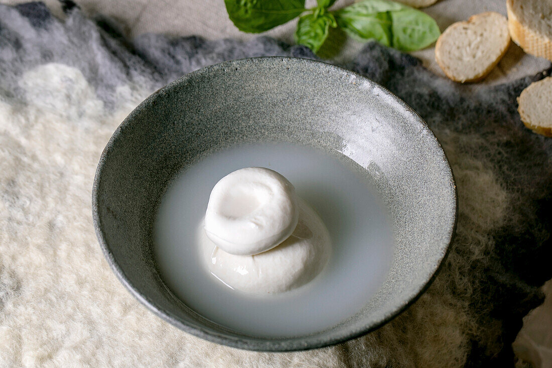 Traditional italian burrata knotted cheese in grey ceramic bowl on table