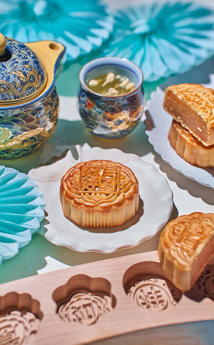 Traditioneller Mondkuchen mit Füllung, Backform, Teekanne und Teebecher mit Kräutertee