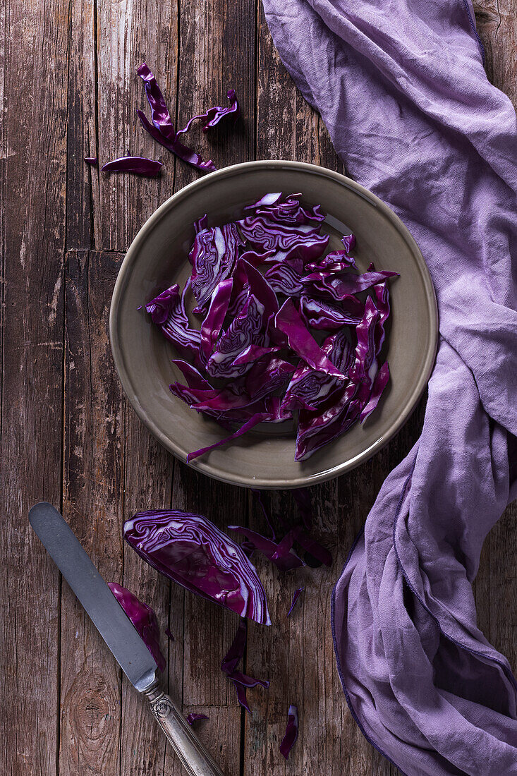 Red cabbage sliced leaves placed on rustic wooden table