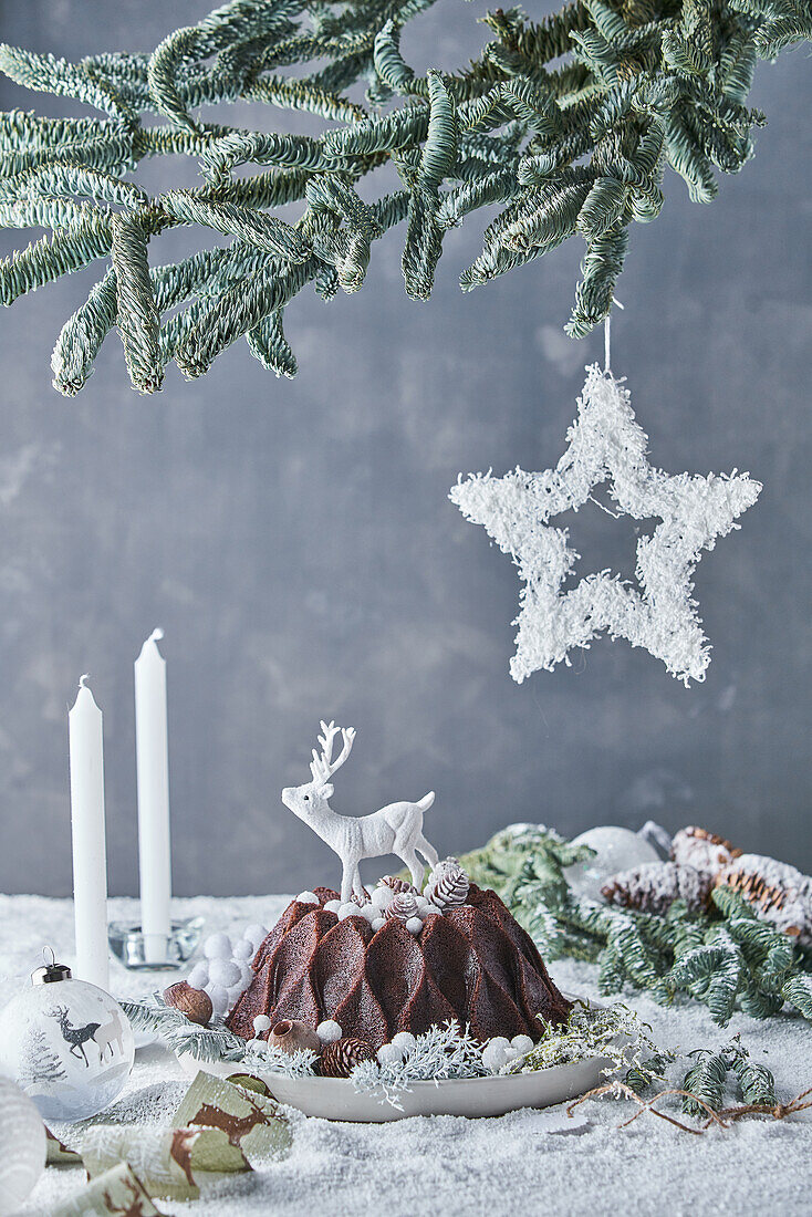 Chocolate bundt cake decorated with deer served on decorated Christmas table with candles