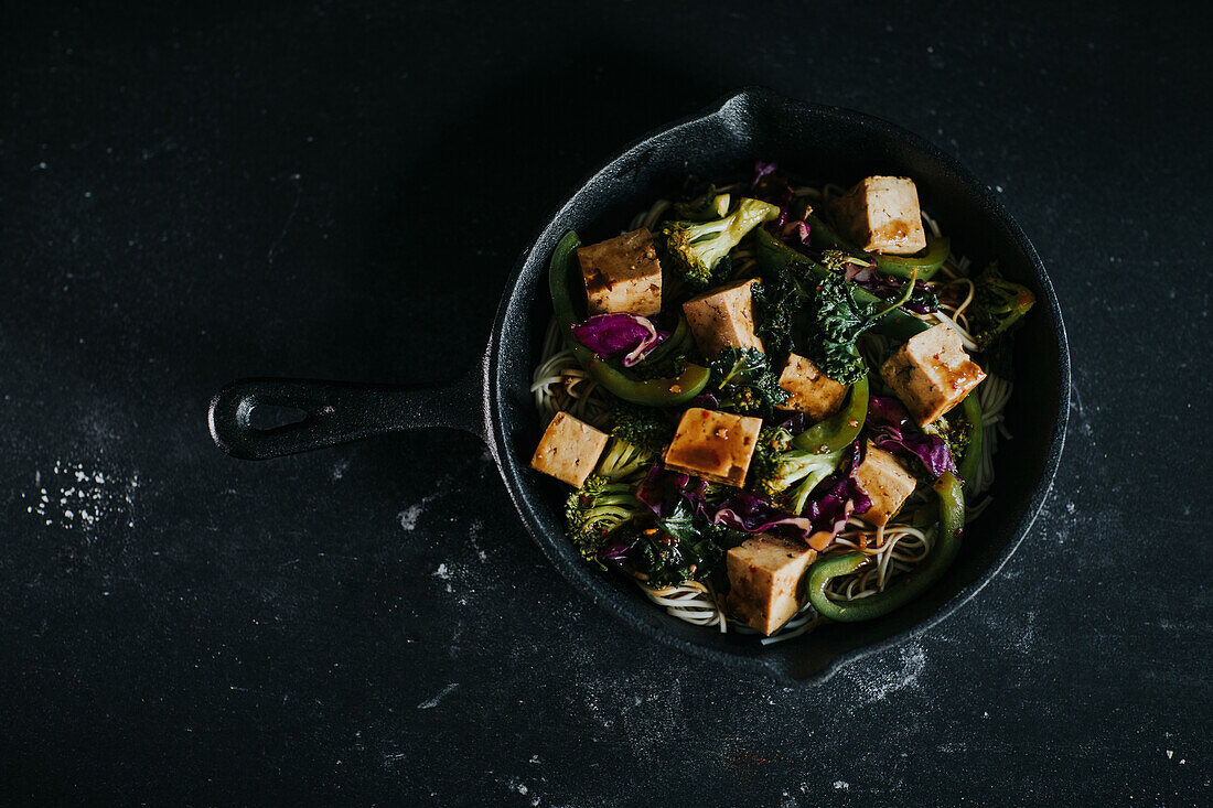 Vegetarischer Salat mit gebratenem Tofu und Gemüse auf schwarzem Untergrund