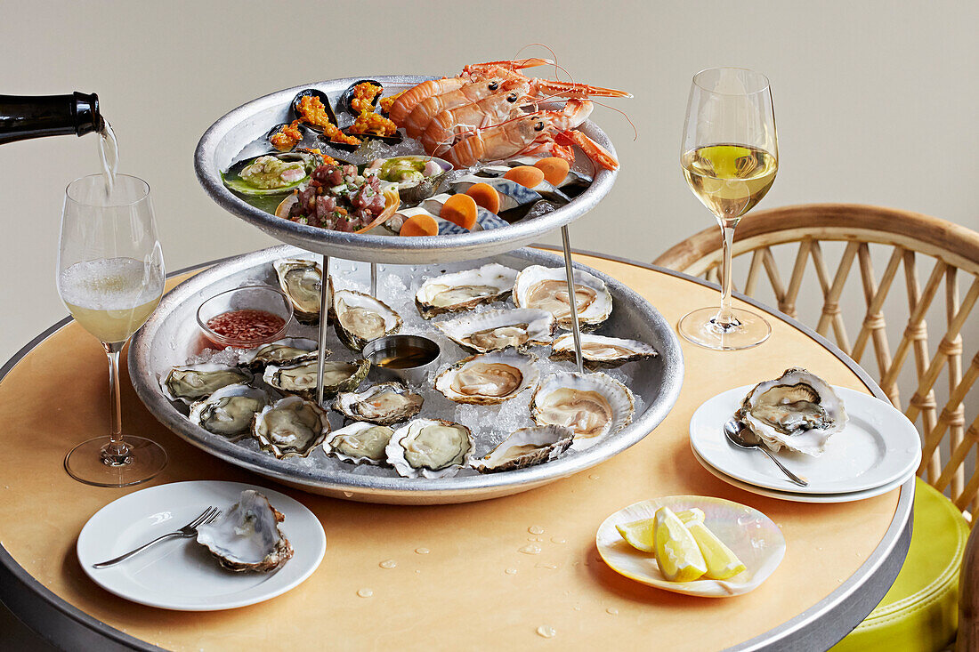 Seafood sharing plates with white wine being poured