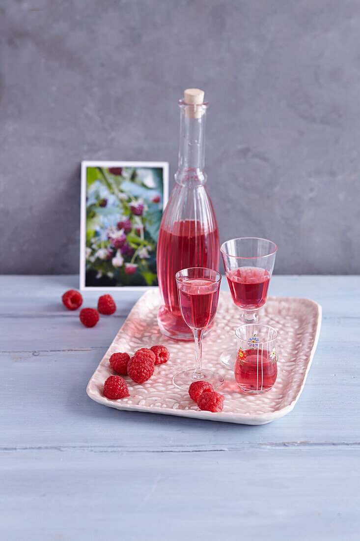 Raspberry liqueur in carafe and glasses on tray