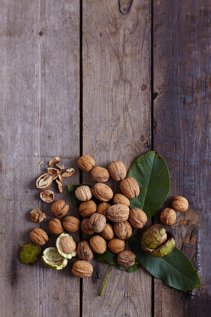 Walnuts with shells and leaves on a wooden background
