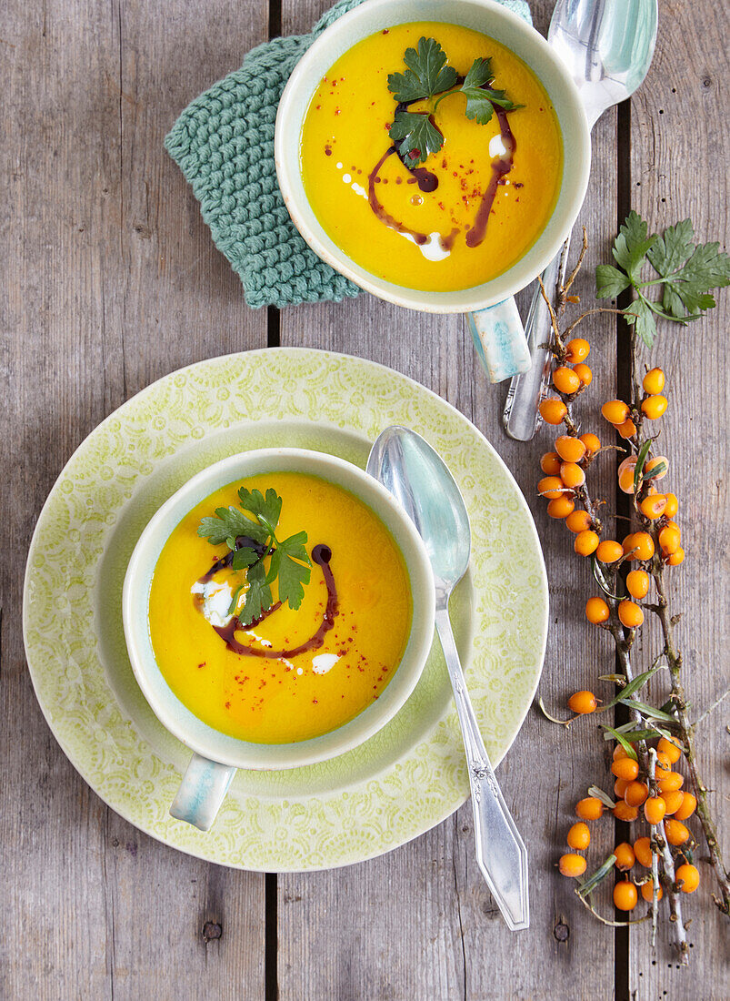 Buckthorn, pumpkin, and carrot soup in bowl next to buckthorn branch