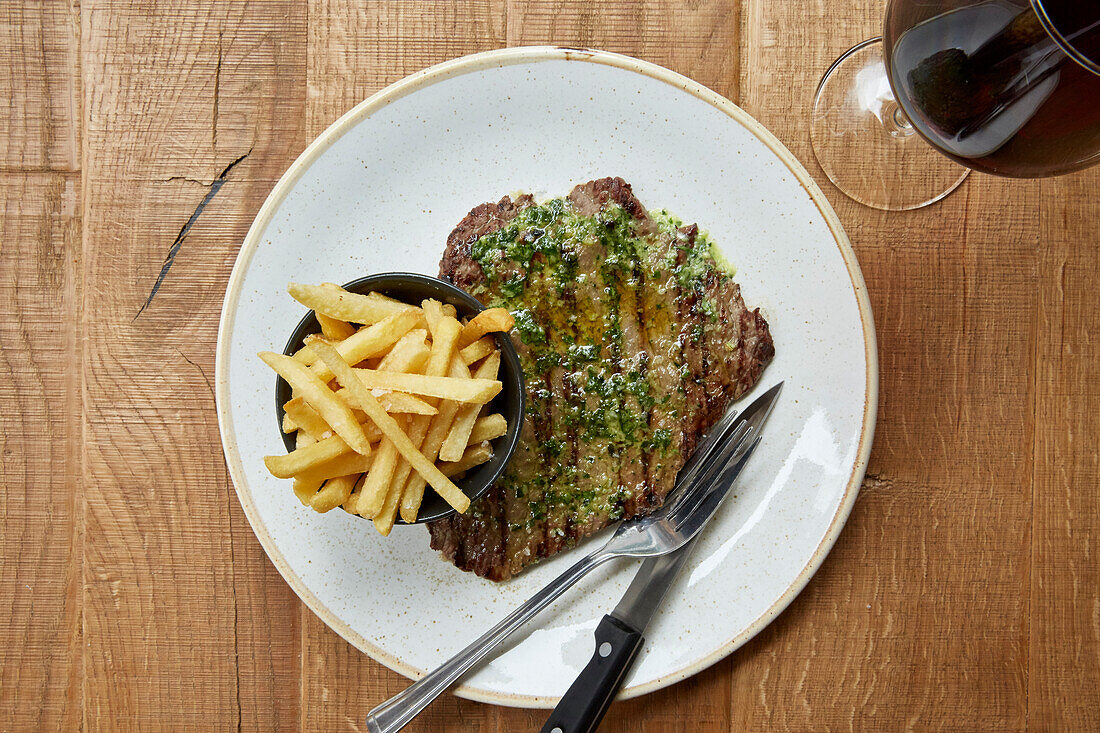 Steak with a herb sauce and fries