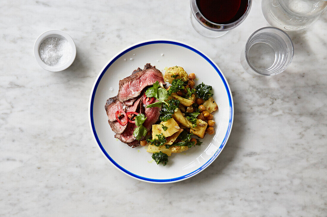 Thinly sliced beef served with vegetable salad with kale, cauliflower, and chickpeas