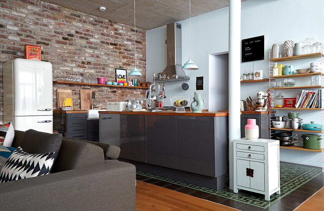 Modern kitchen and seating area in loft with brick wall