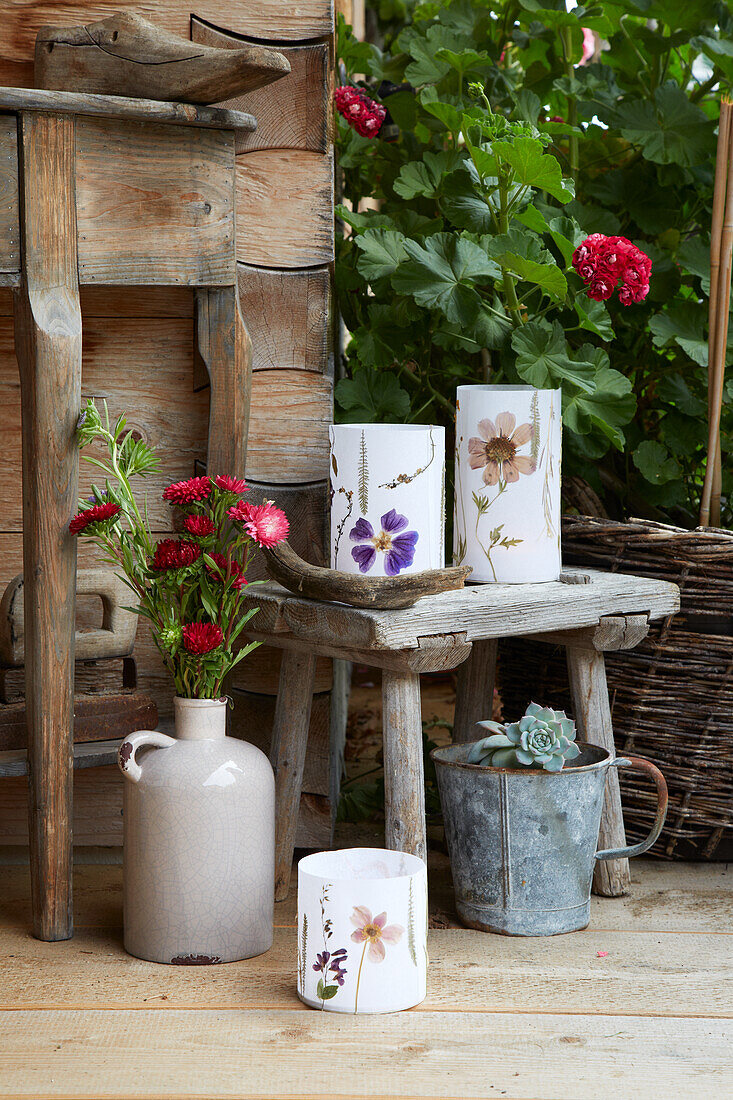 Garden decoration made of lanterns with dried flowers, vase with flowers, wooden stool and succulent plant