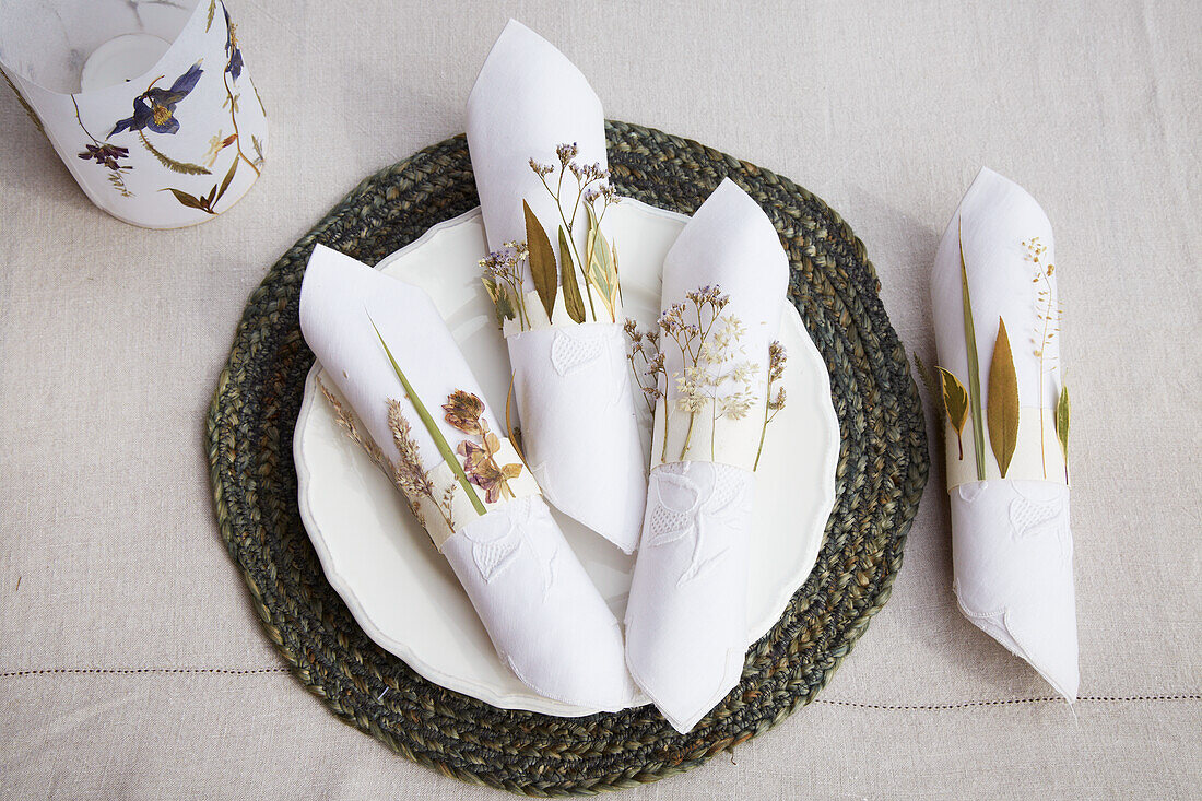 Napkins with DIY paper napkin holders and dried flowers on placemat