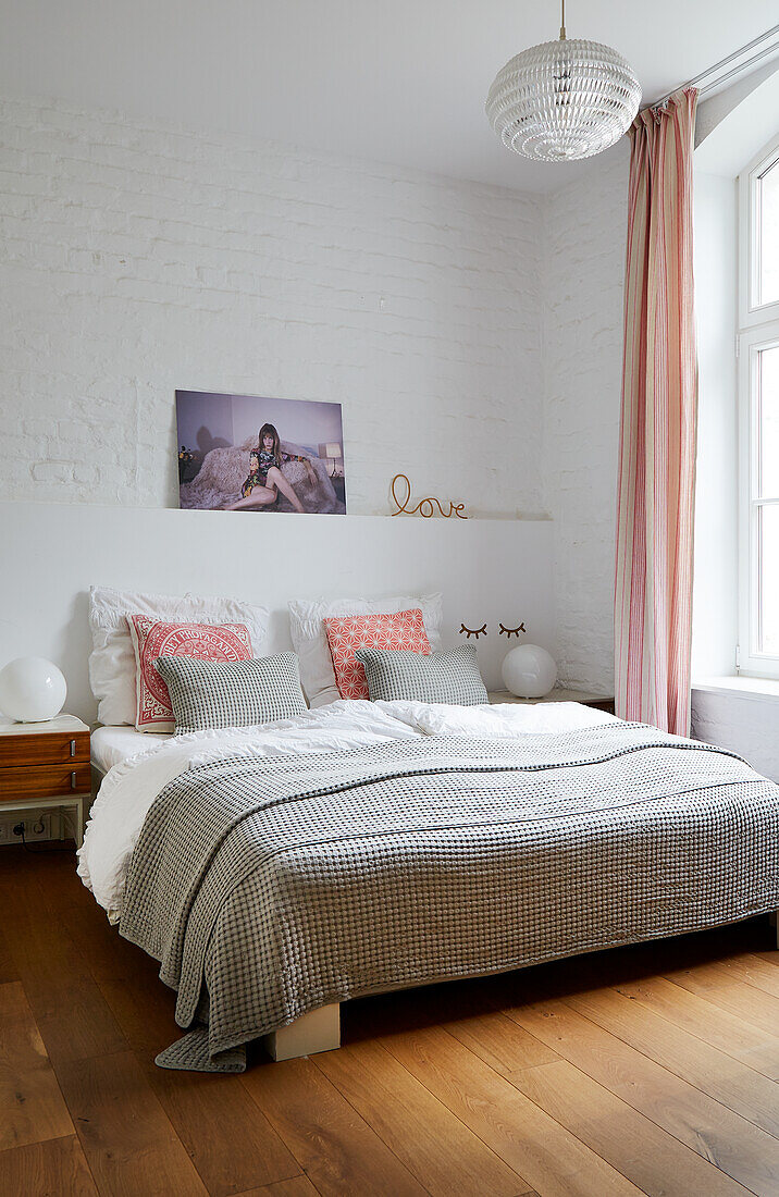 Double bed with grey bedspread in light, airy bedroom